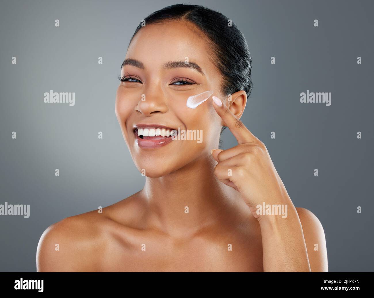 Dont you forget to moisturise. Shot of a beautiful young woman applying moisturiser to her face. Stock Photo