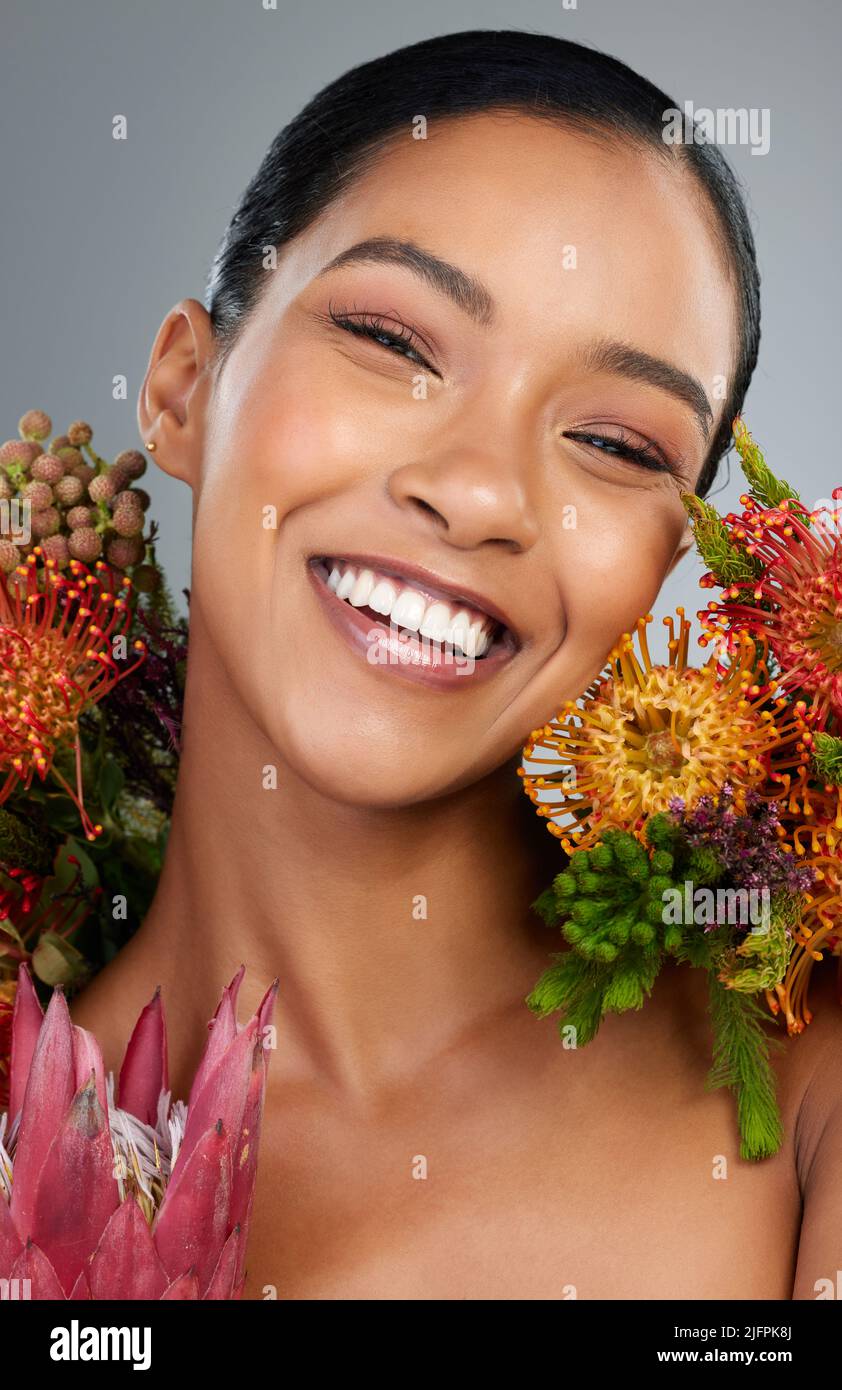 Beautiful things never go unnoticed. Studio shot of a beautiful young woman posing with fynbos flowers. Stock Photo