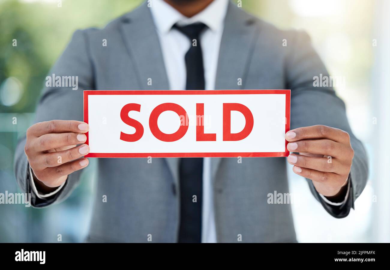 To the highest bidder you go. Cropped shot of an unrecognizable businessman holding up a sold sign while standing in the office. Stock Photo