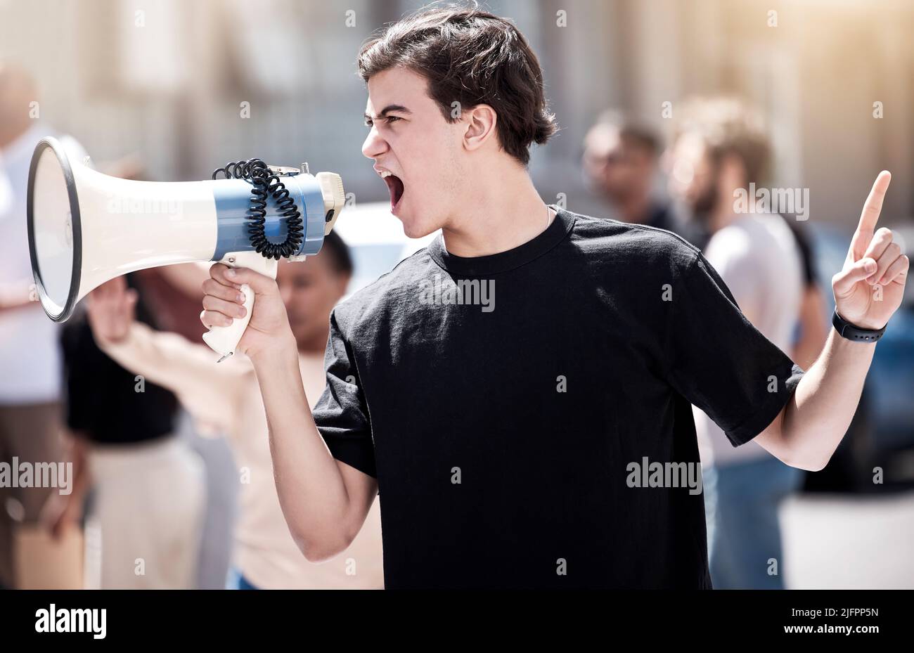 We will not be silenced. Shot of a young man yelling through a megaphone during a protest. Stock Photo