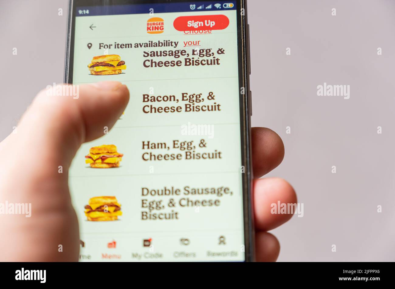 Man orders food on his phone. Male hand chooses hamburger on menu