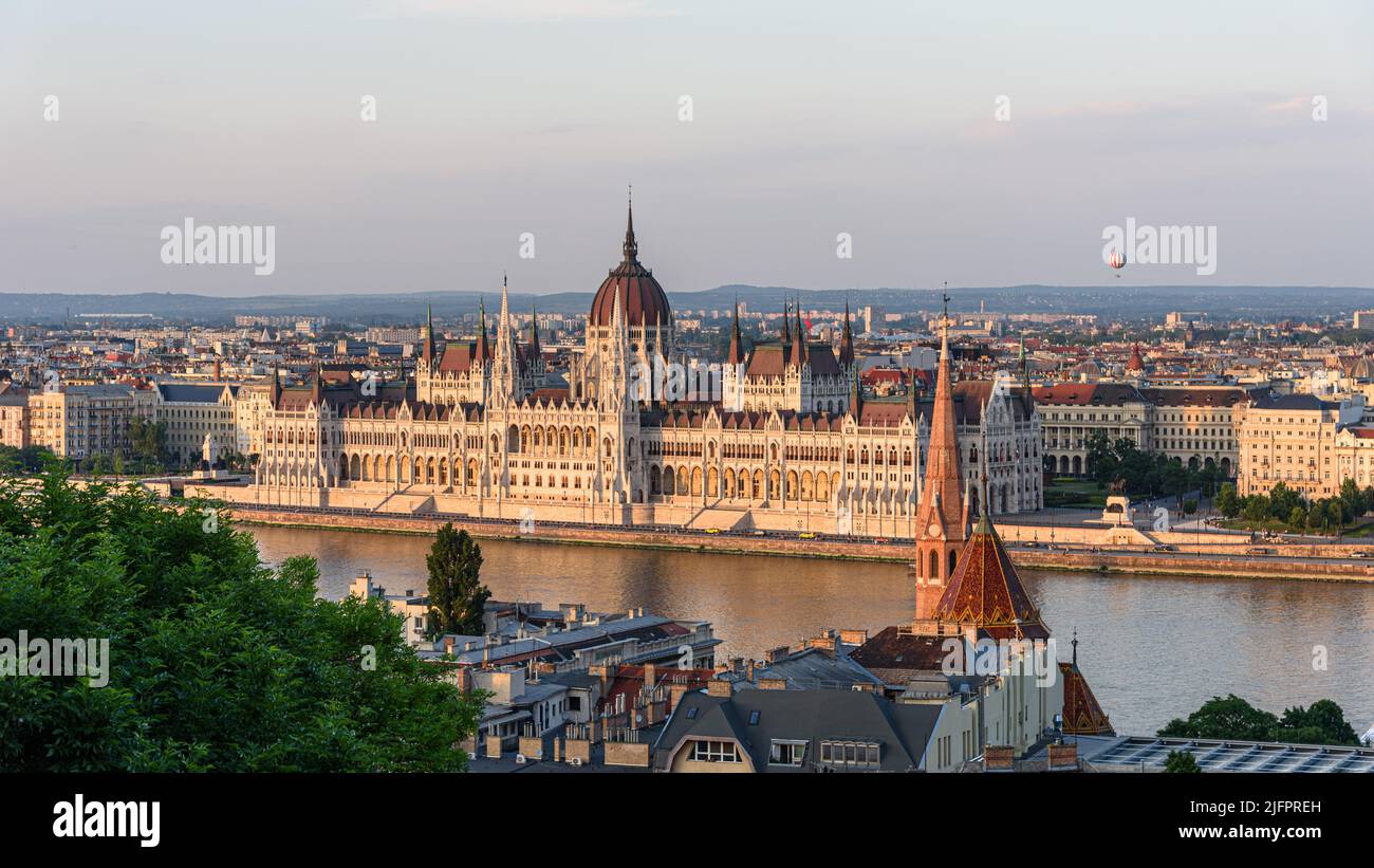 The Hungarian parliament building at golden hour with a hot air balloon in the distance Stock Photo