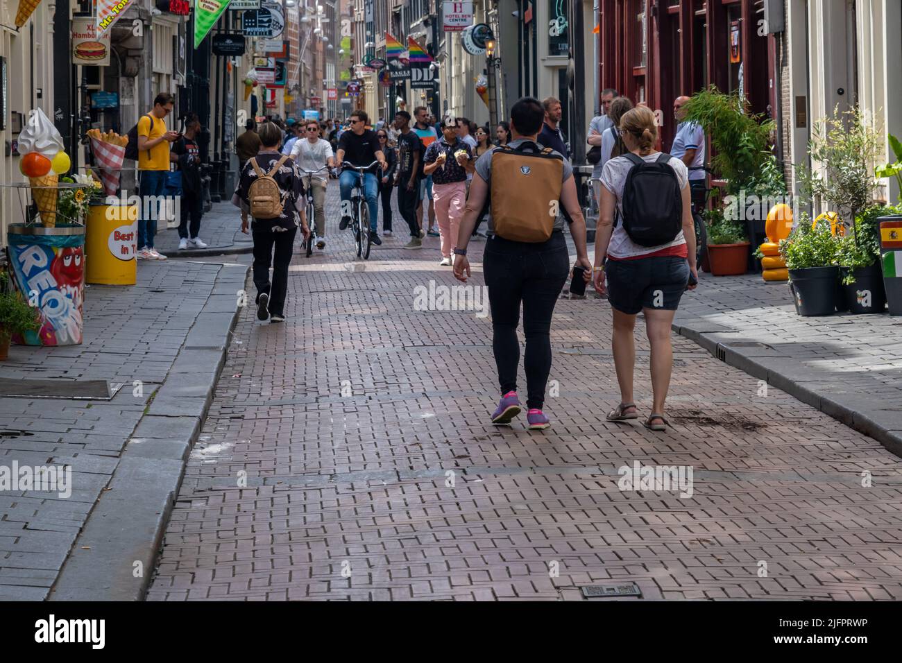 Amsterdam, The Netherlands - 21 June 2022: People walking on narrow street with many stores Stock Photo