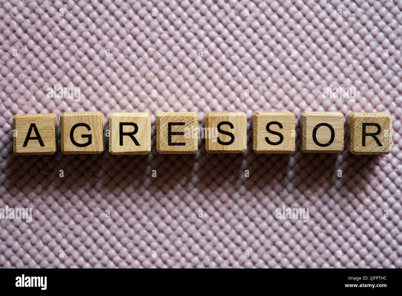 Aggressor word collected with wooden cubes on light background Stock Photo