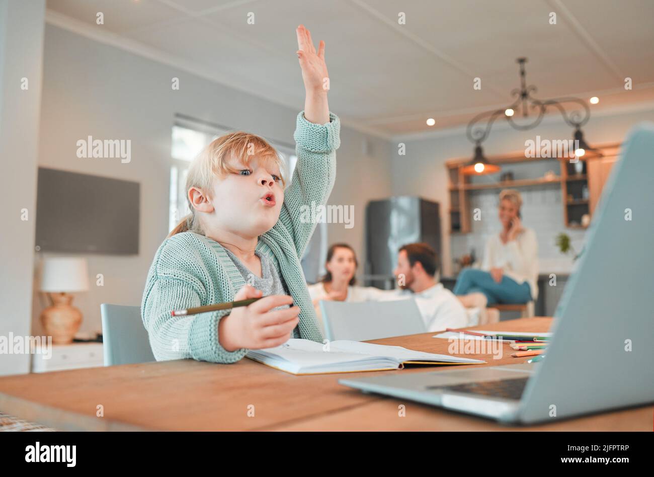 Home schooling girl with her hand in the air. Cute caucasian child using a laptop to attend classes remotely. Asking and answering questions in class Stock Photo