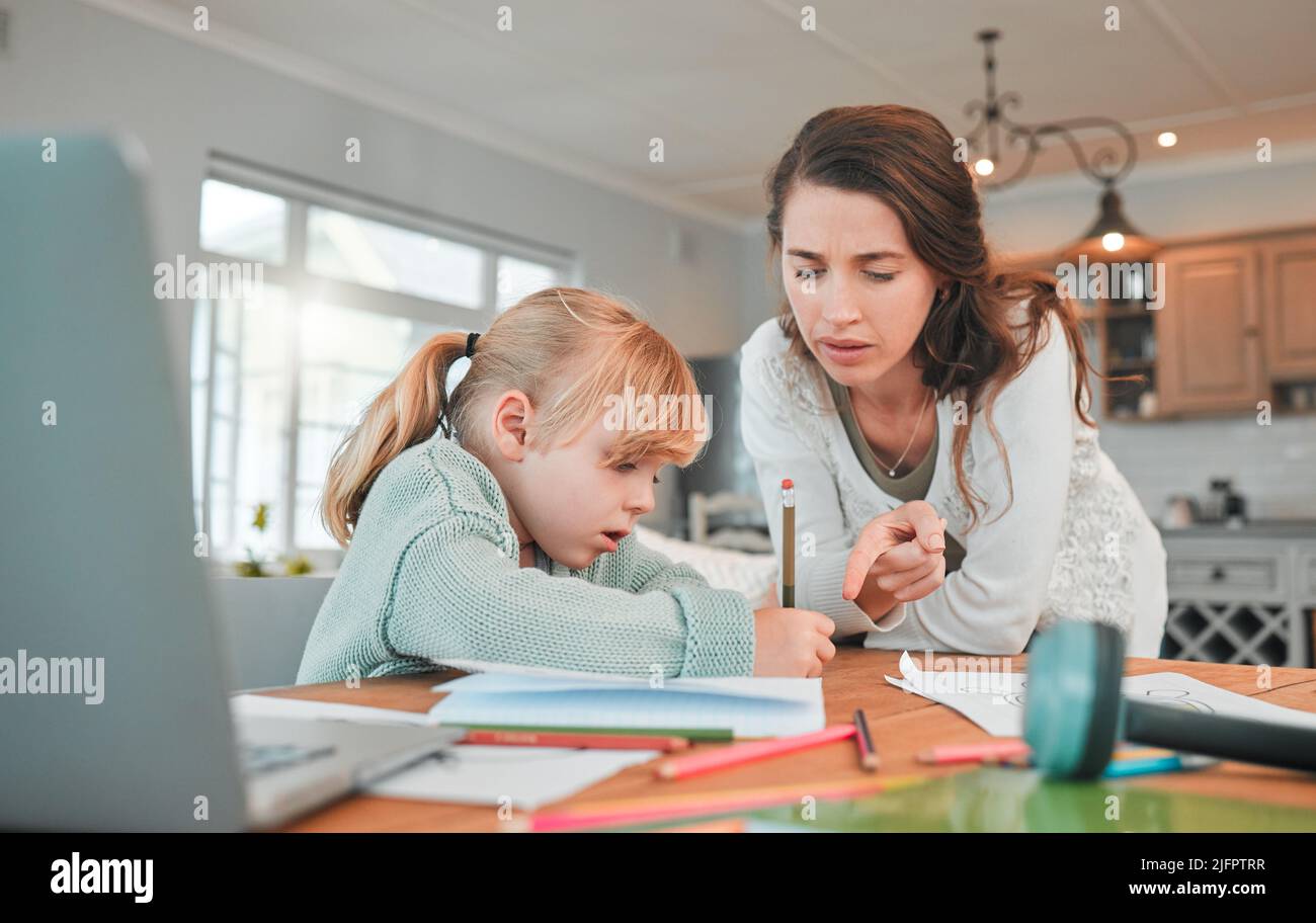 Adorable little caucasian girl sitting at table and doing homework ...