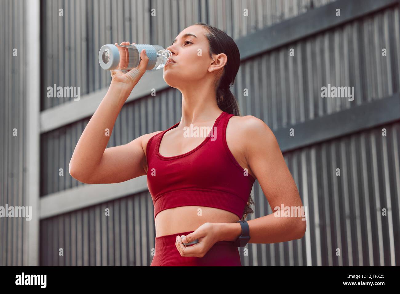 Staying hydrated. Cropped shot of an attractive young female athlete drinking water while