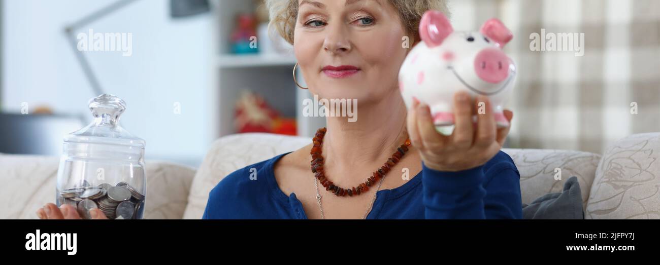 Senior woman on pension weighing containers with saved money for future Stock Photo