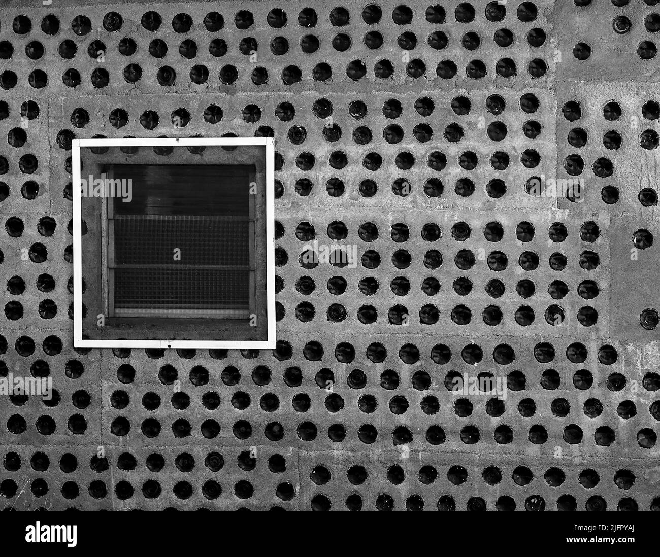 An old concrete wall filled with round holes and displaying a white