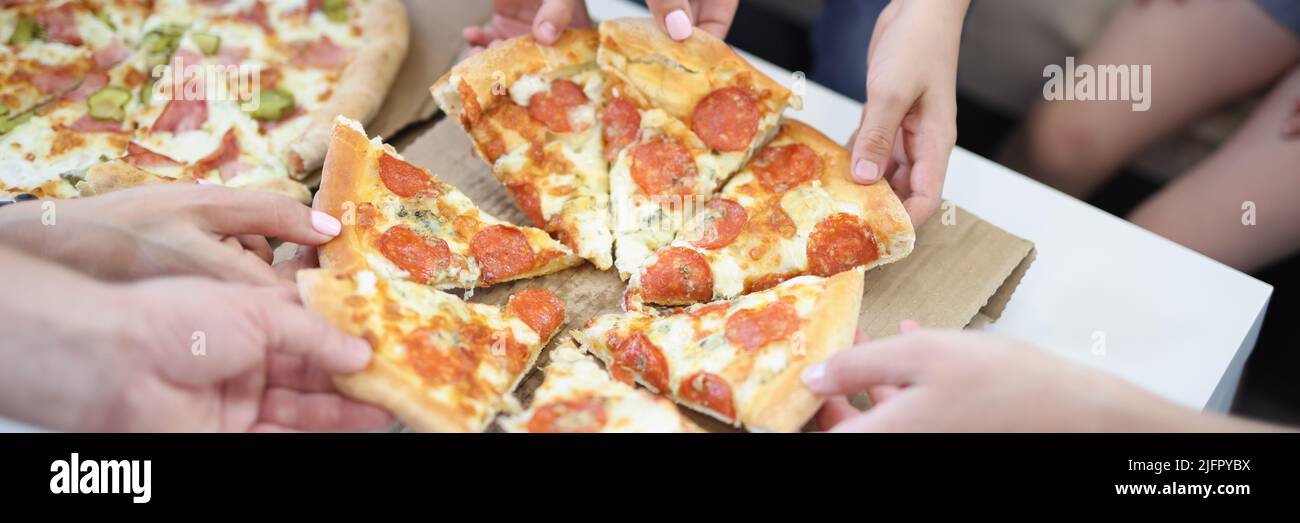 Hands of big company take piece of round shaped pizza Stock Photo