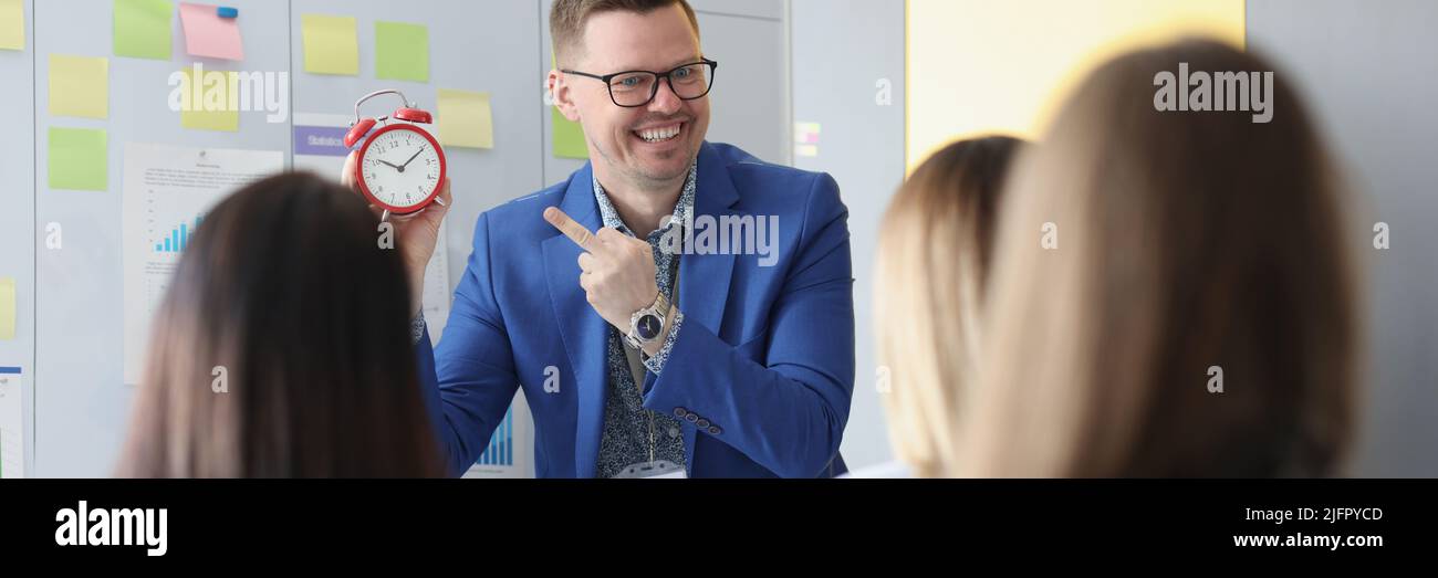 Man speech giver stand in from of colleagues and explain that time is money Stock Photo