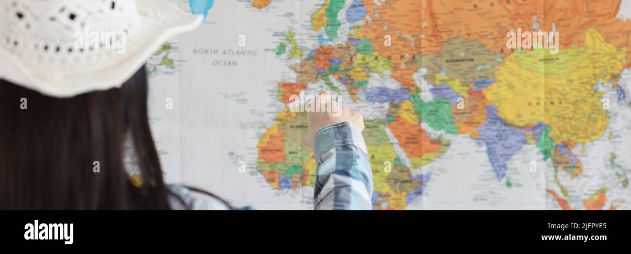 Woman point on world map with finger and decide what country to go next Stock Photo