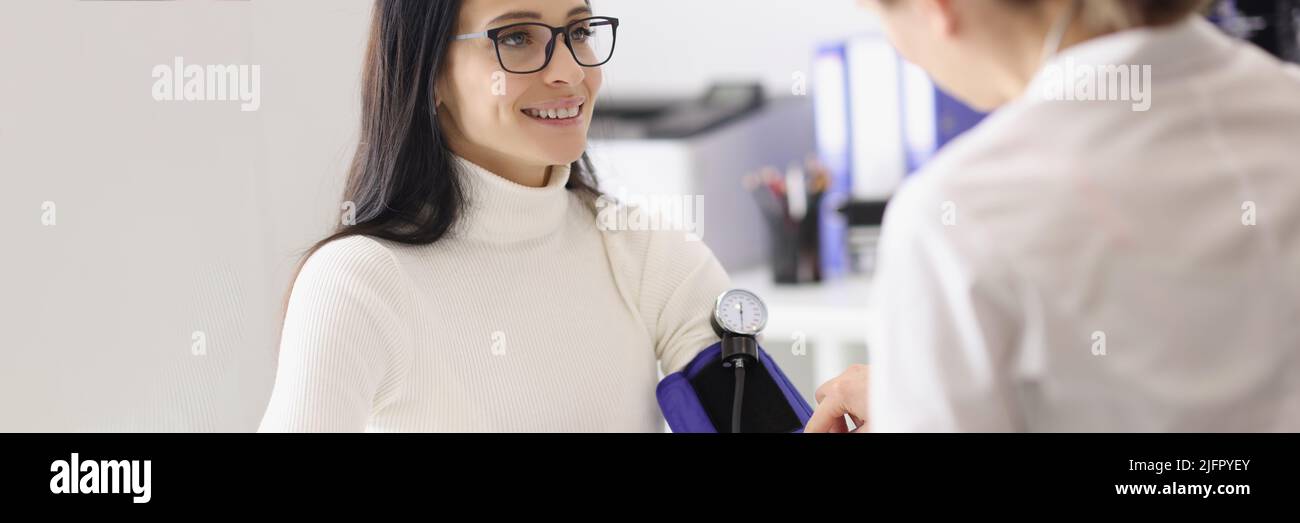 Doctor measuring patients blood pressure with tonometer tool and talk Stock Photo