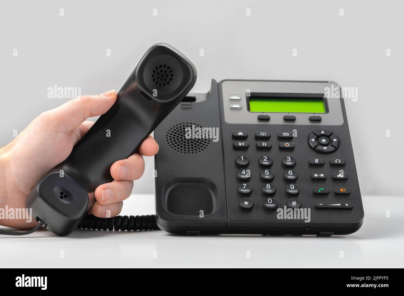 hand holding voip telephone receiver on gray background. Dialing