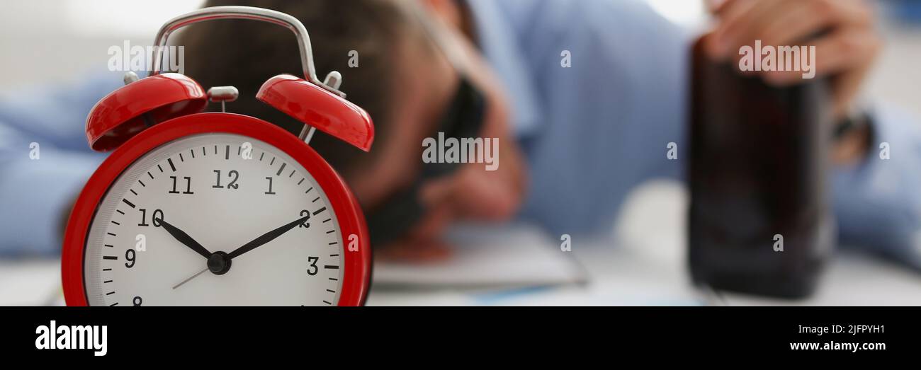 Red vintage clock show time, drunk man fell asleep on workplace in office Stock Photo