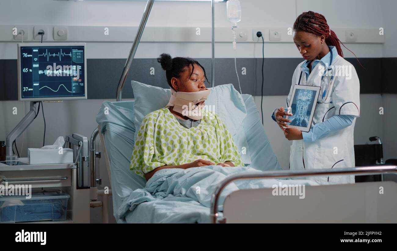Specialist showing x ray scan to patient with cervical collar laying in
