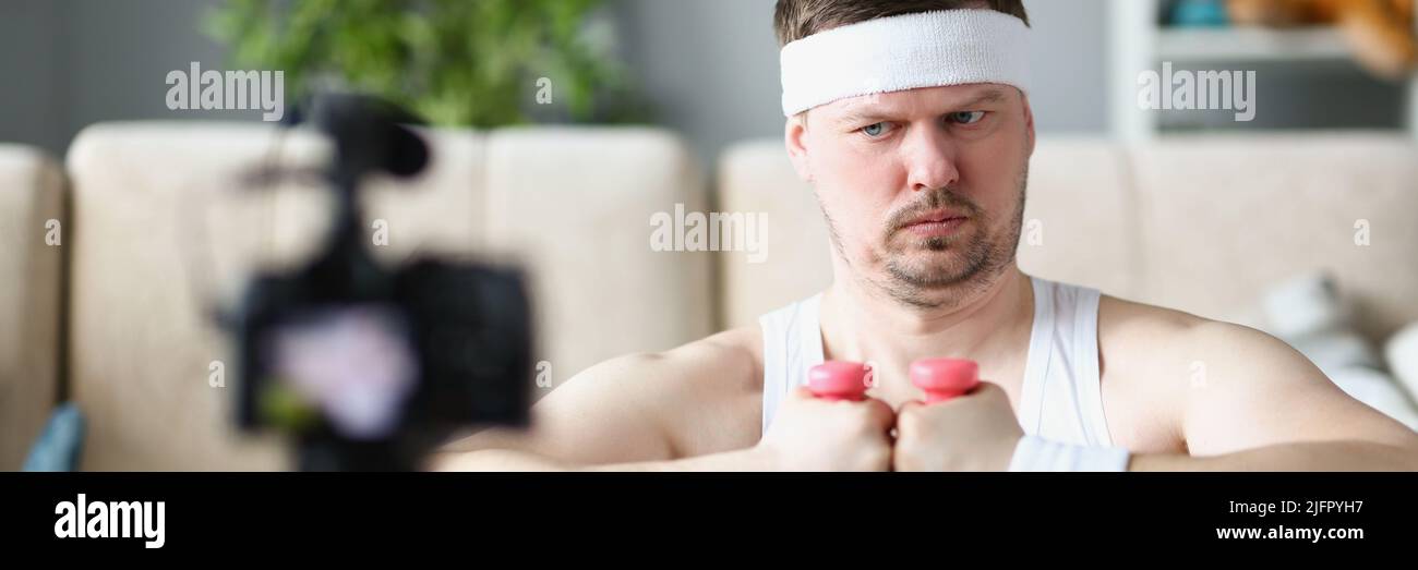 Strong middle aged man train on camera using pink dumbbells Stock Photo