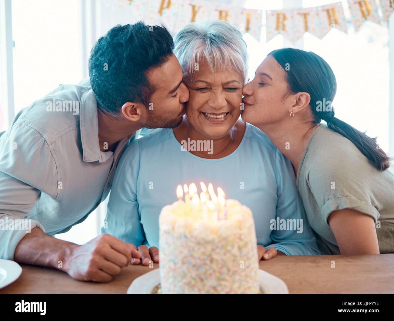 We love you. Shot of two young adults celebrating a birthday with a mature woman at home. Stock Photo