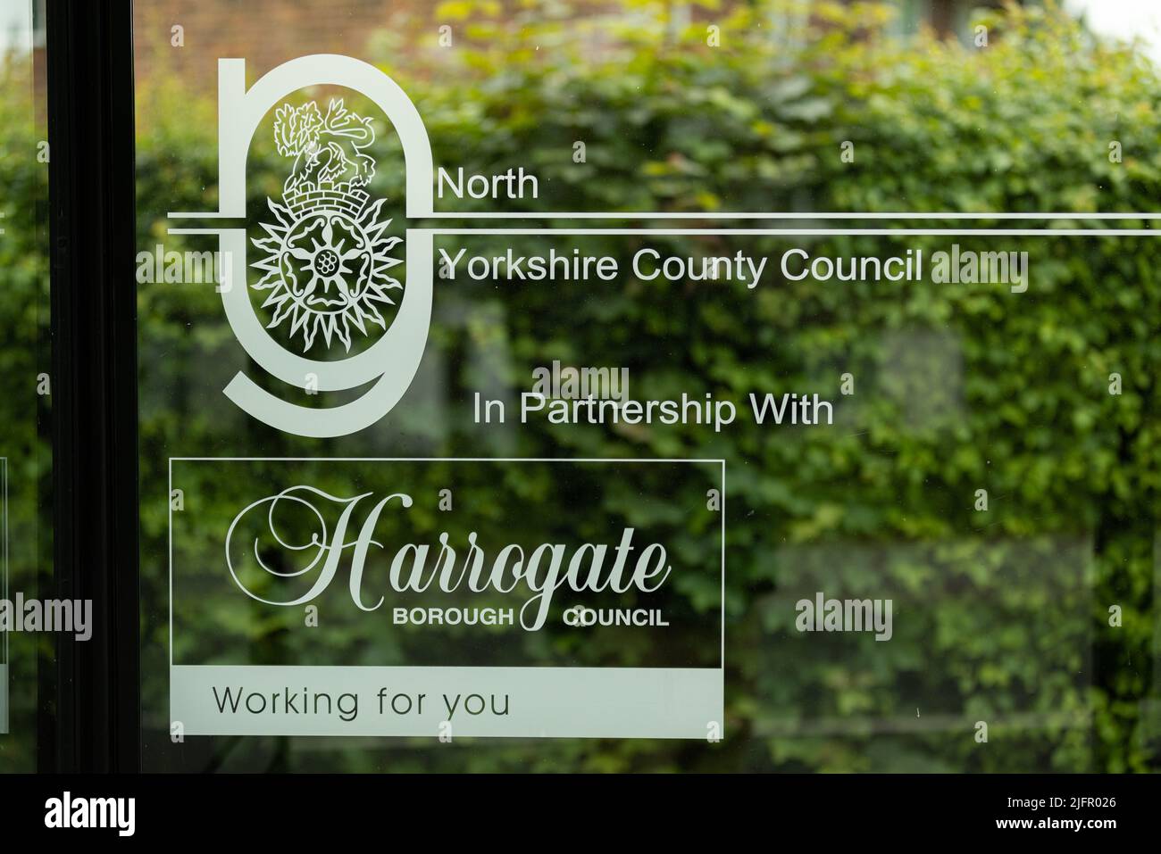 Public bus stop window saying North Yorkshire country council in partnership with Harrogate borough council Stock Photo