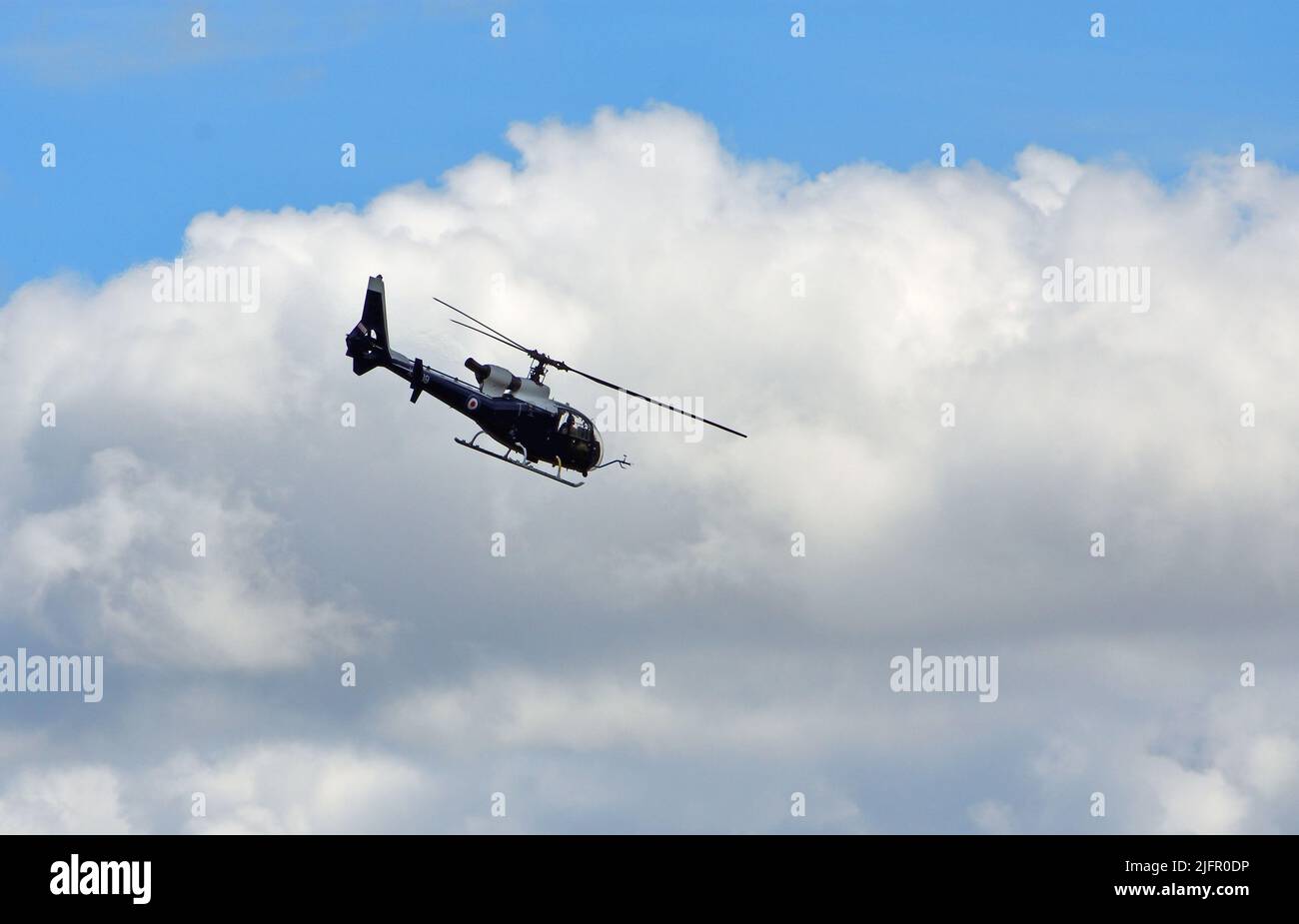 Aérospatiale Gazelle  helicopter in flight against Cloudy Sky. Stock Photo