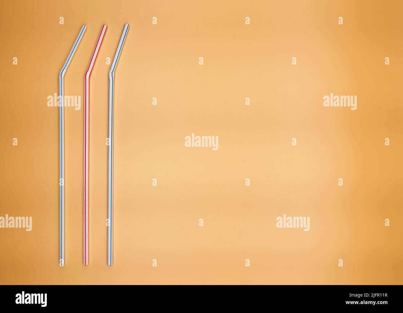 Colorful drinking straws isolated on orange background. Stock Photo