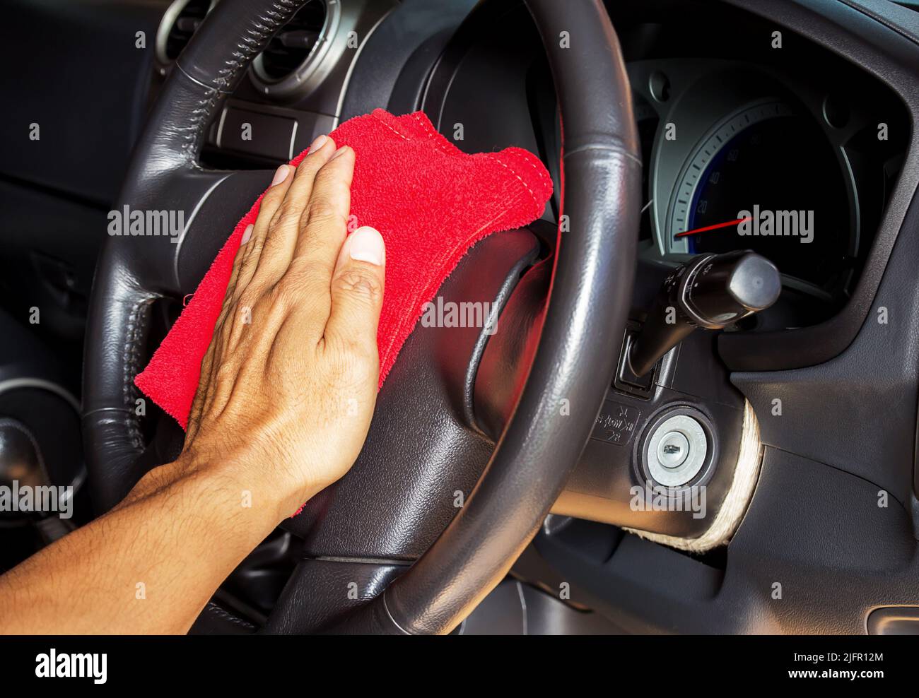 Hand with microfiber cleaning a car steering wheel auto detailing