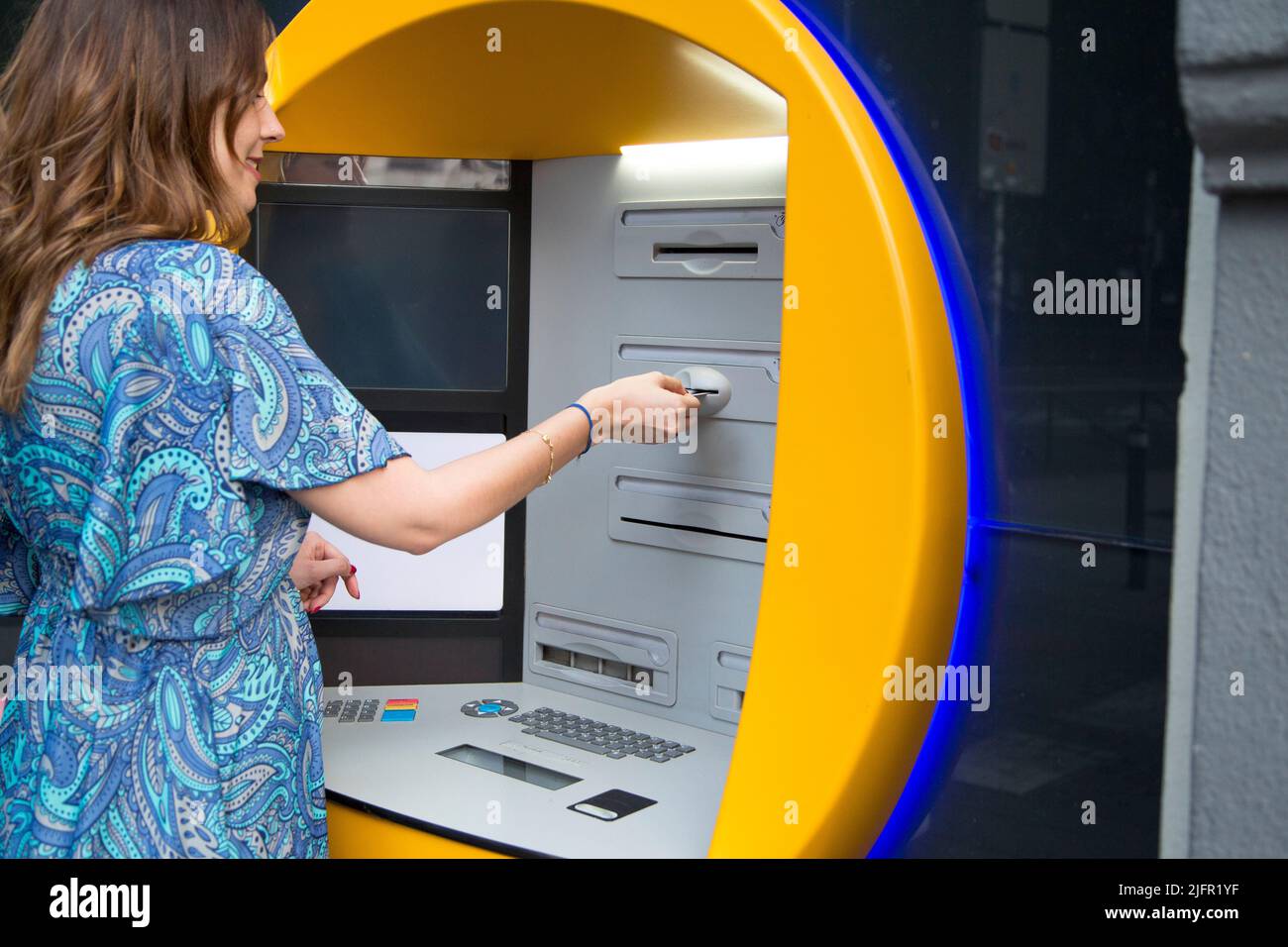 Cropped photo of a caucasian woman withdrawing money from the ATM Stock Photo