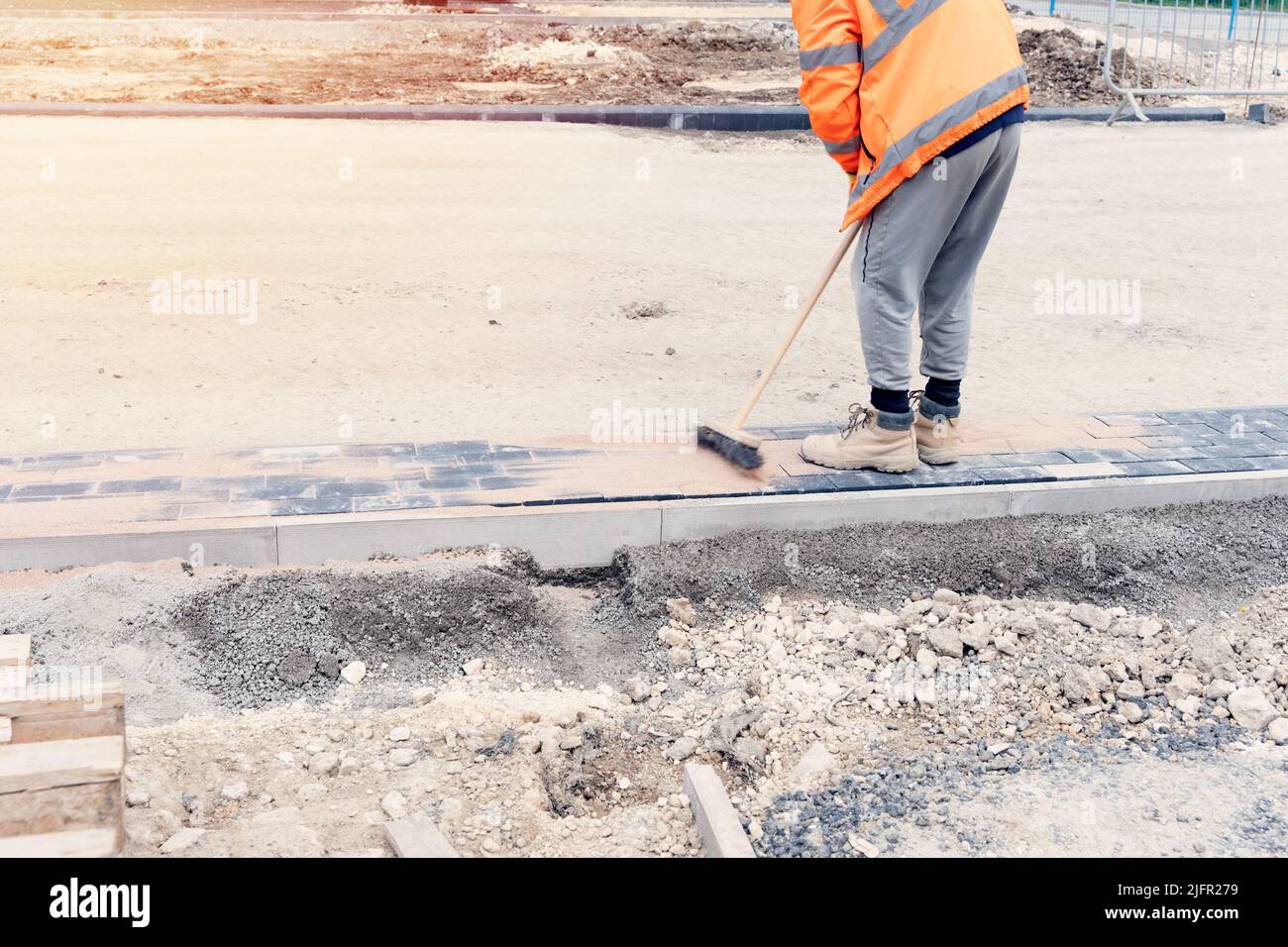 Paving stone workers filling joints of the block paved footpath with