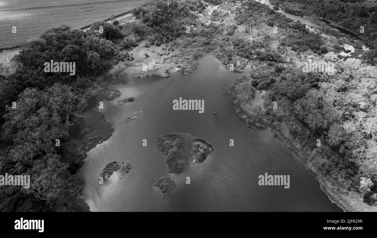 Drone aerial of a dammed river showing small flows of water amongst bushland. Stock Photo