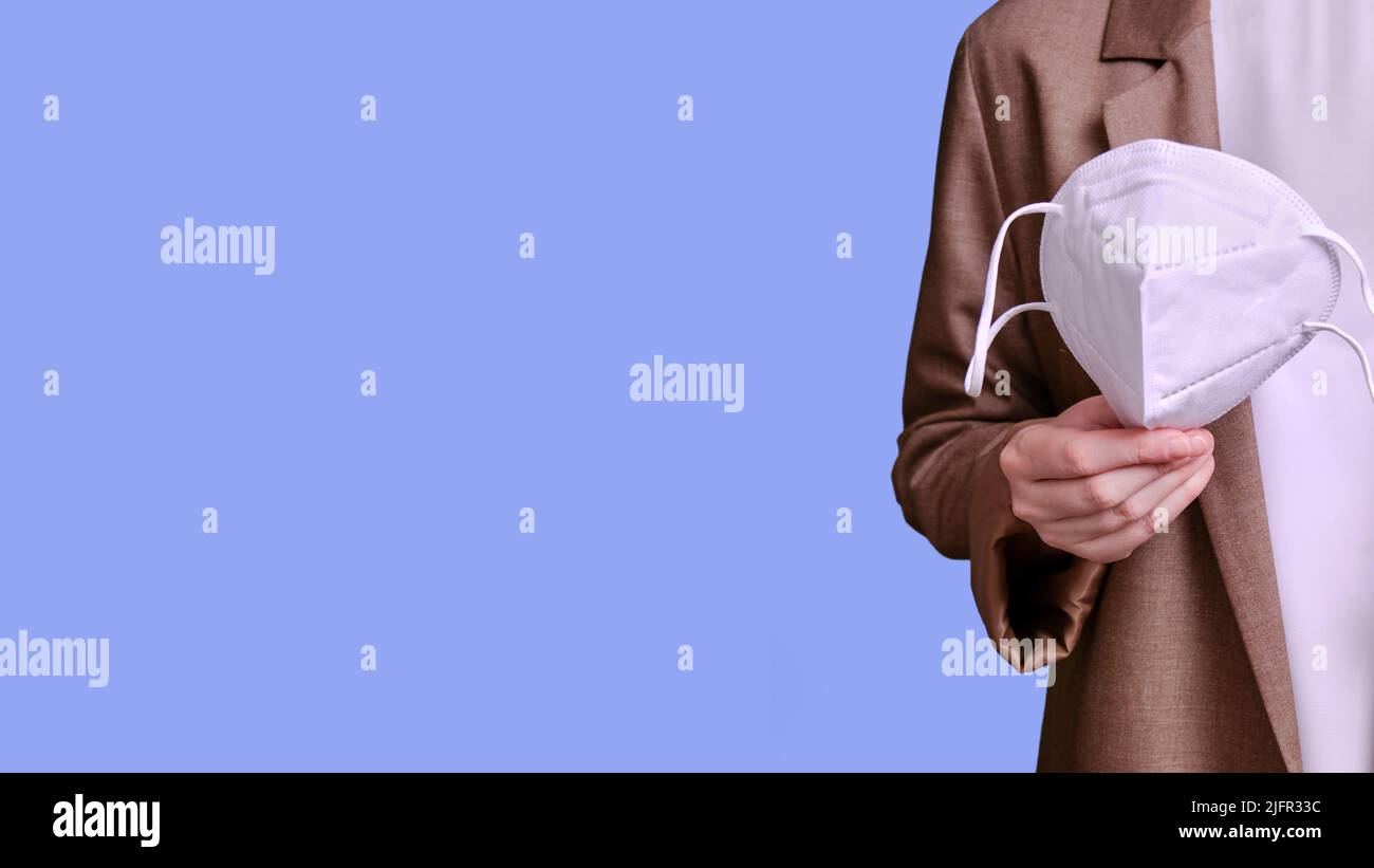 Woman teacher holding n95 medical mask on studio blue background ...