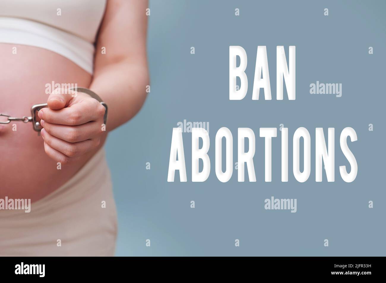 Text about the ban on abortions and chained hands of a pregnant woman, studio shot on a blue background Stock Photo