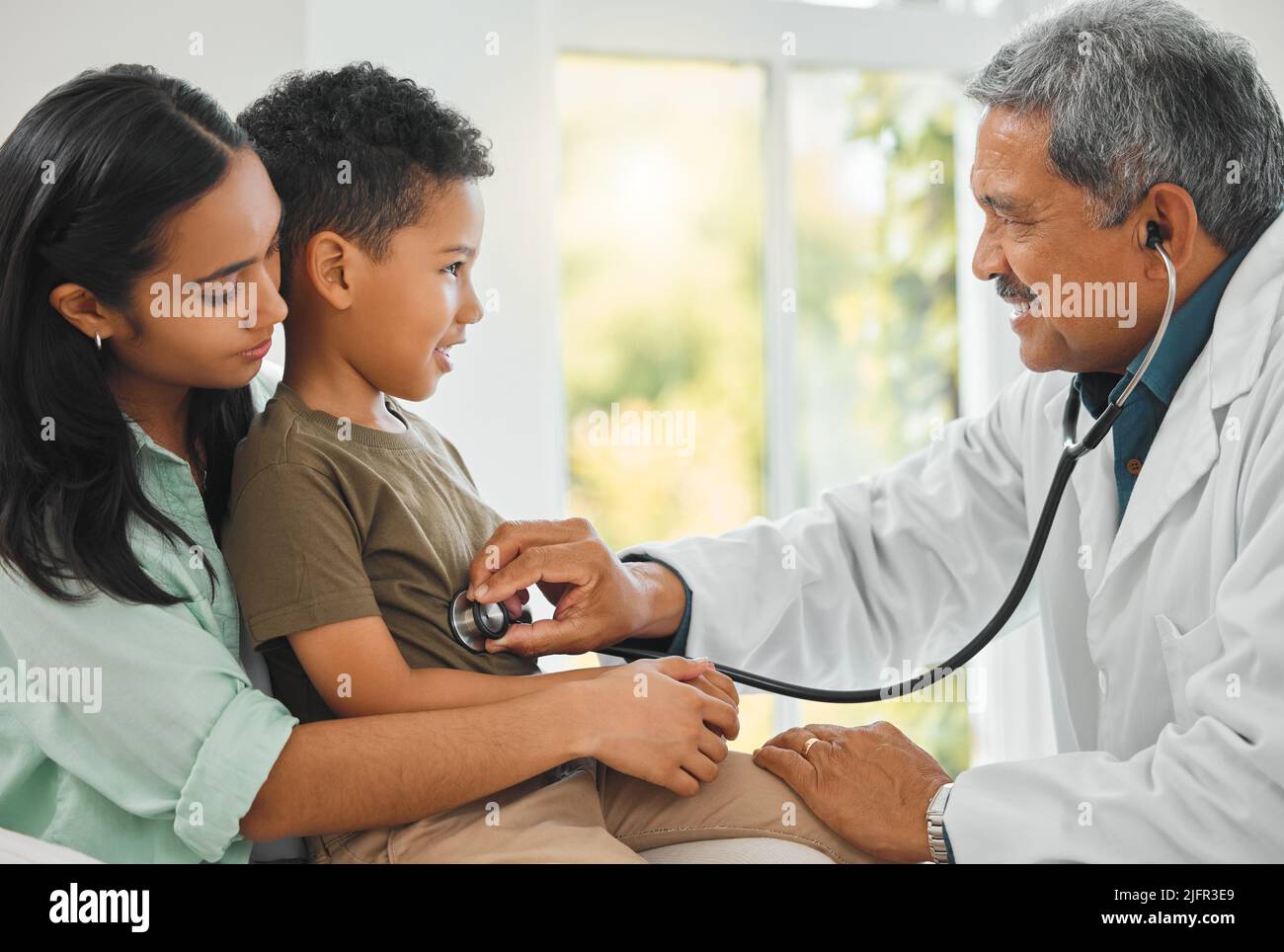 Youre a healthy boy. shot of a mature doctor doing a checkup on a little boy at home. Stock Photo