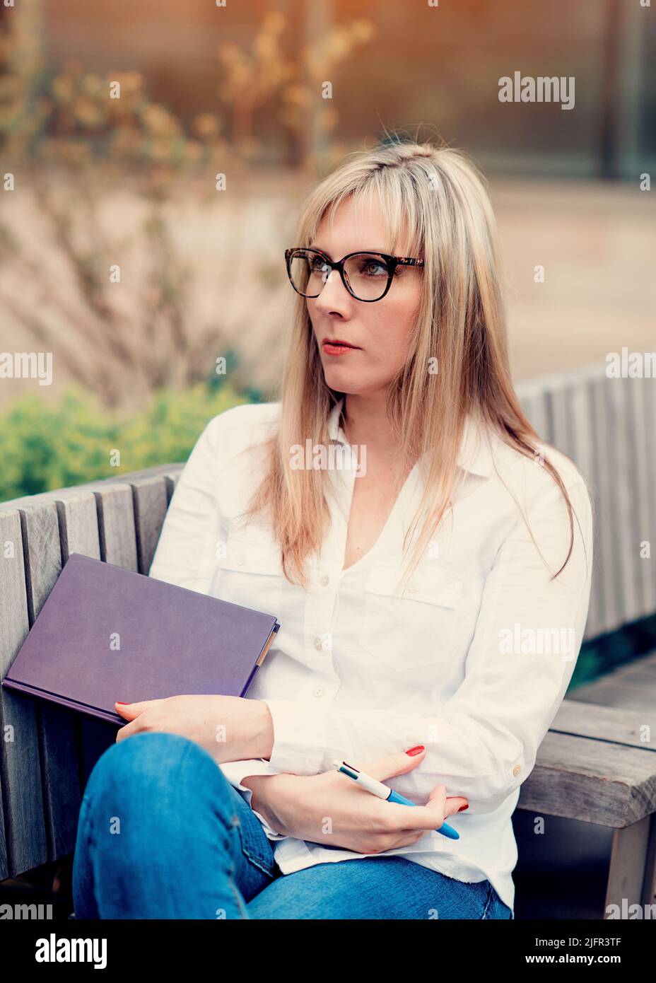 woman holding a notebook and sitting  in park in city Stock Photo