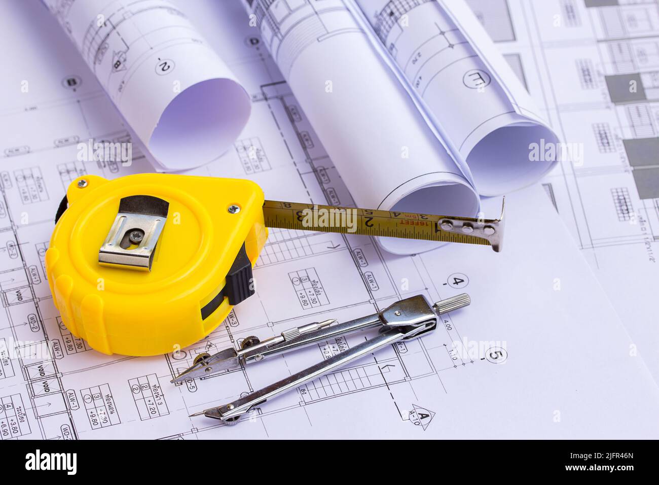 Tape measure and pencil compasses over a construction plan drawing for