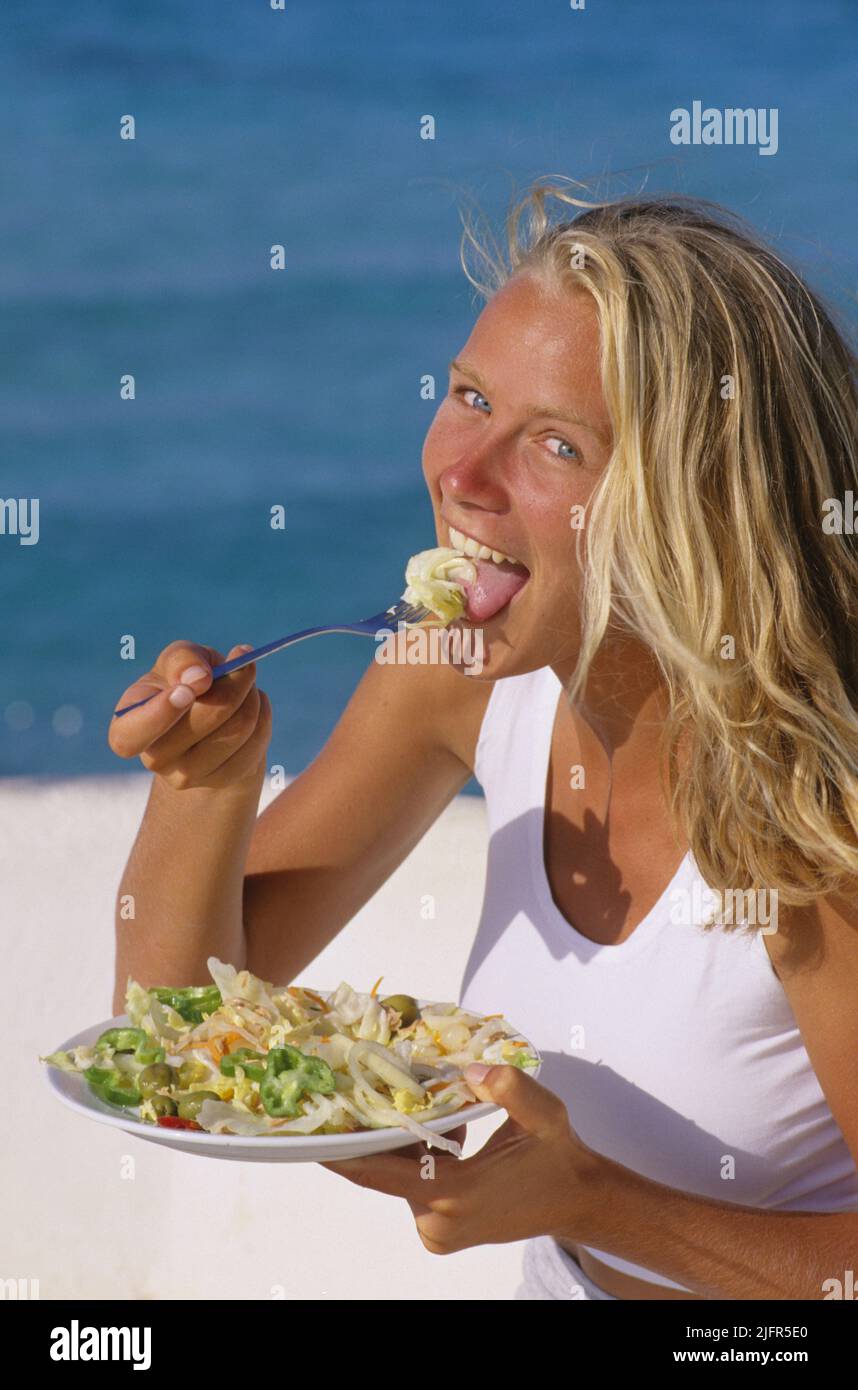 pretty blond hair young woman eating salad Stock Photo