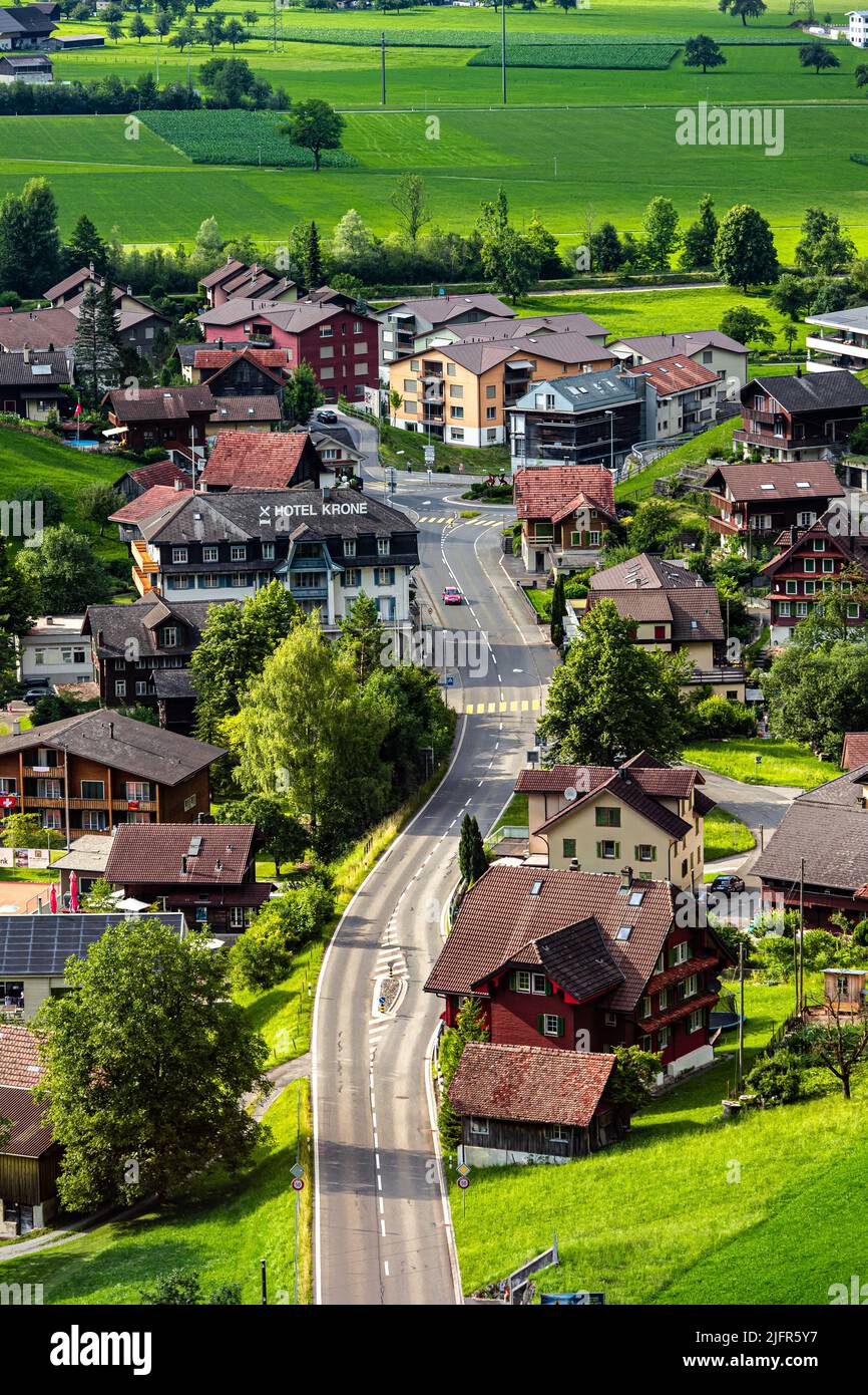 Sarnen, Switzerland - 07 03 2022: Scenery along Golden Pass Line - Swiss Town. Swiss chalets by the road. A red car on the road. Stock Photo
