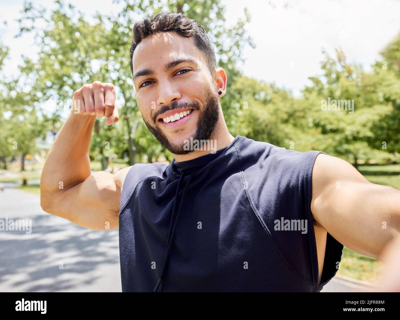 Biceps dont grow on trees. Portrait of a sporty young man flexing his bicep and taking selfies while exercising outdoors. Stock Photo