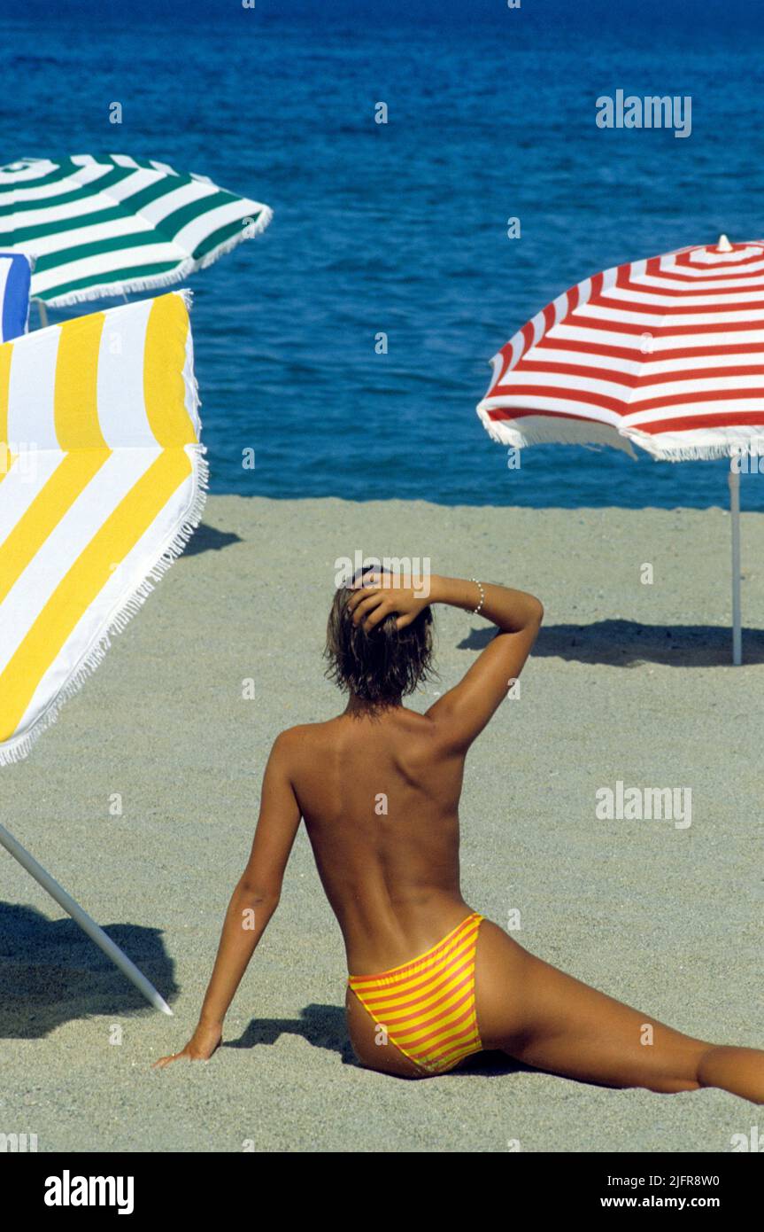 beauty sit on sand of beach looking to seaside nice silhouette with colored umbrellas background Stock Photo