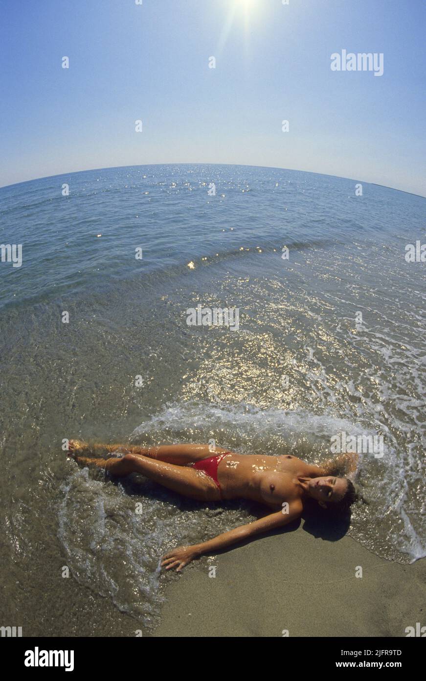 Pretty blond hair lay down on the beach sea water on background fish eyes lens effect blue sky Stock Photo