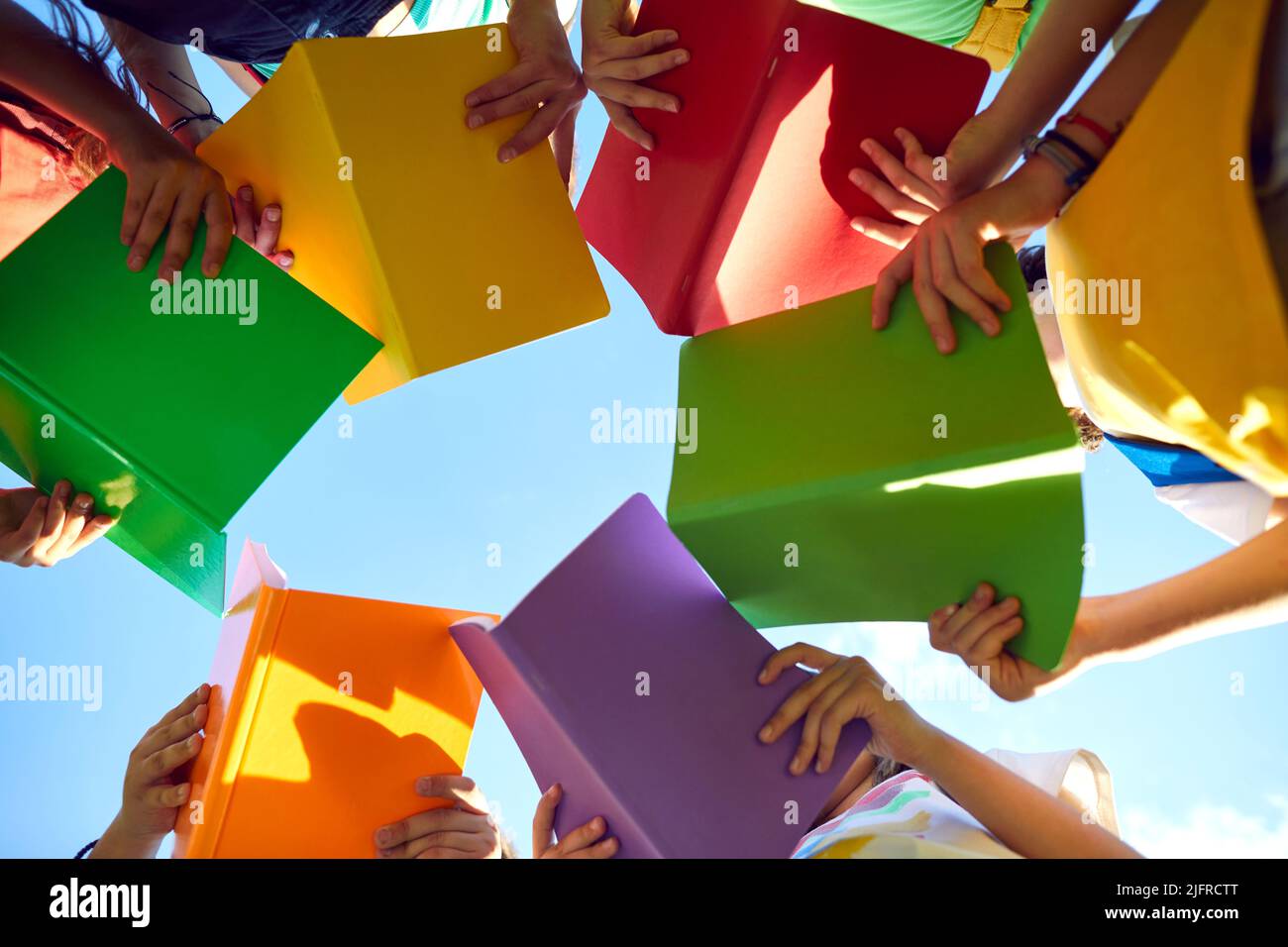 Group of school children learning about our environment and reading books outdoors Stock Photo