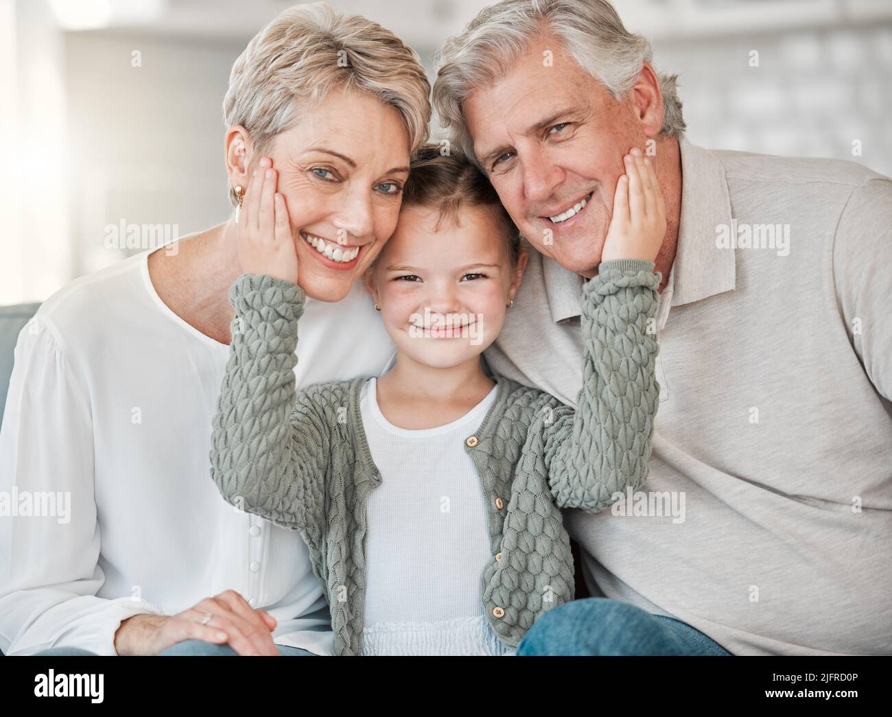 When grandparents enter the door, discipline flies out the window. Shot of a happy senior couple and their granddaughter relaxing on the sofa at home. Stock Photo