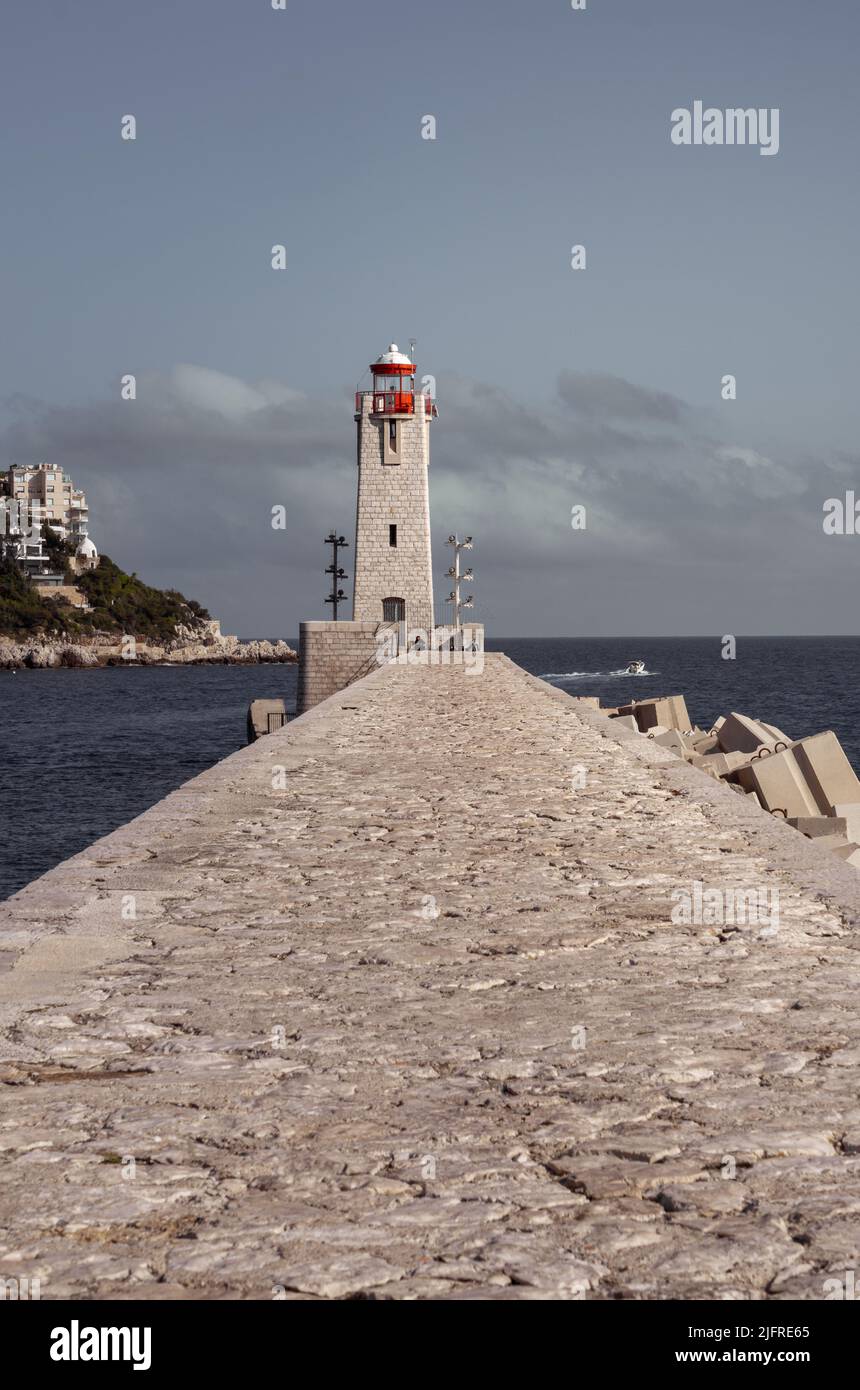 Nice, France, April 2022. The stone path which led to the lighthouse. Dramatic colors and a blue cloudy sky. Stock Photo