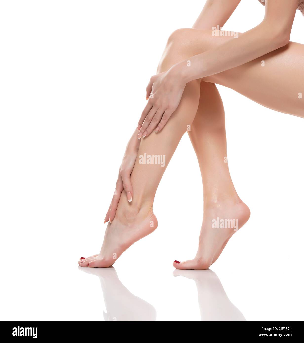 Young woman touching her smooth long legs, and putting on moisturizer