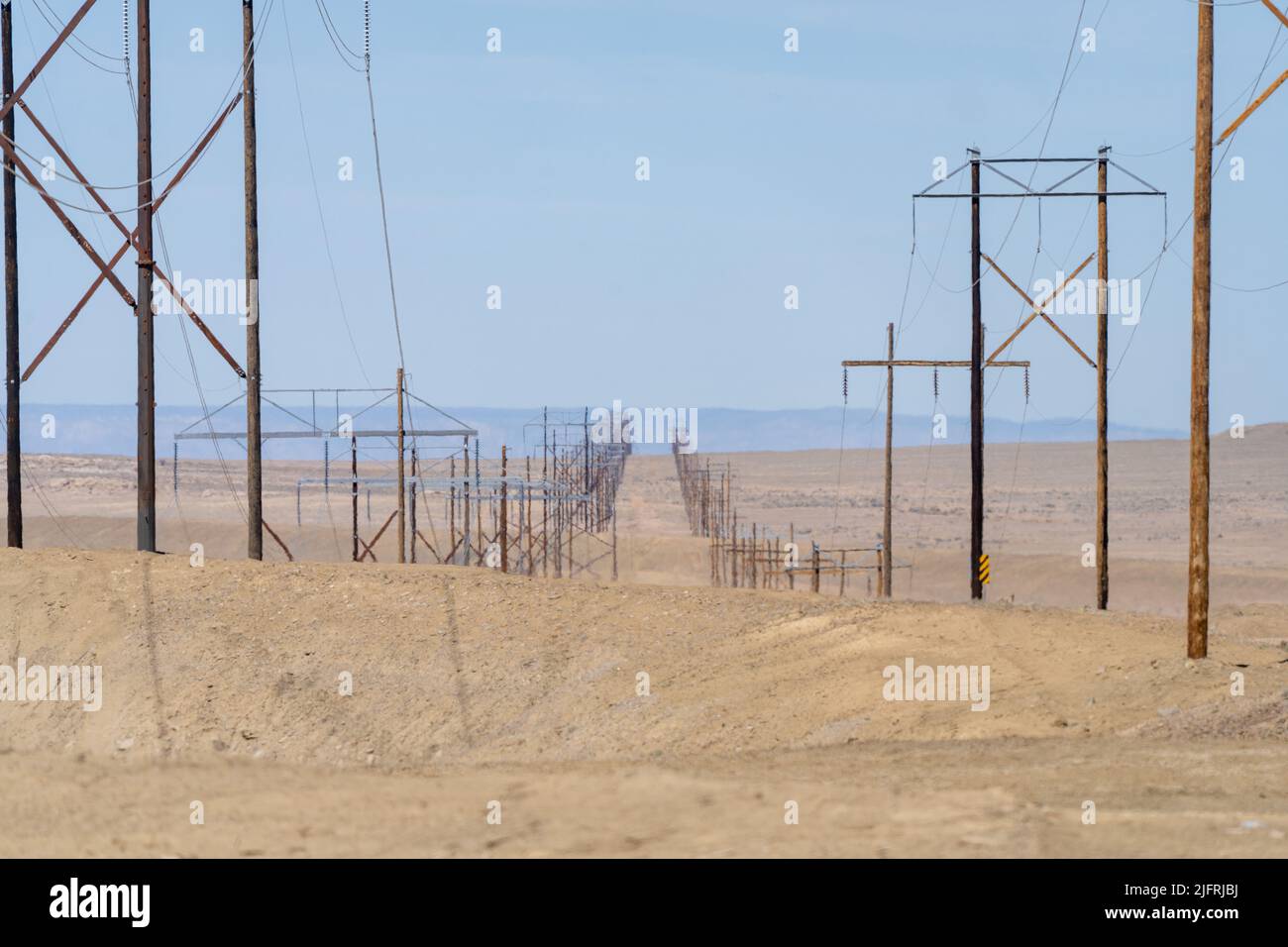 Wooden power transmission line towers stretch out across the barren