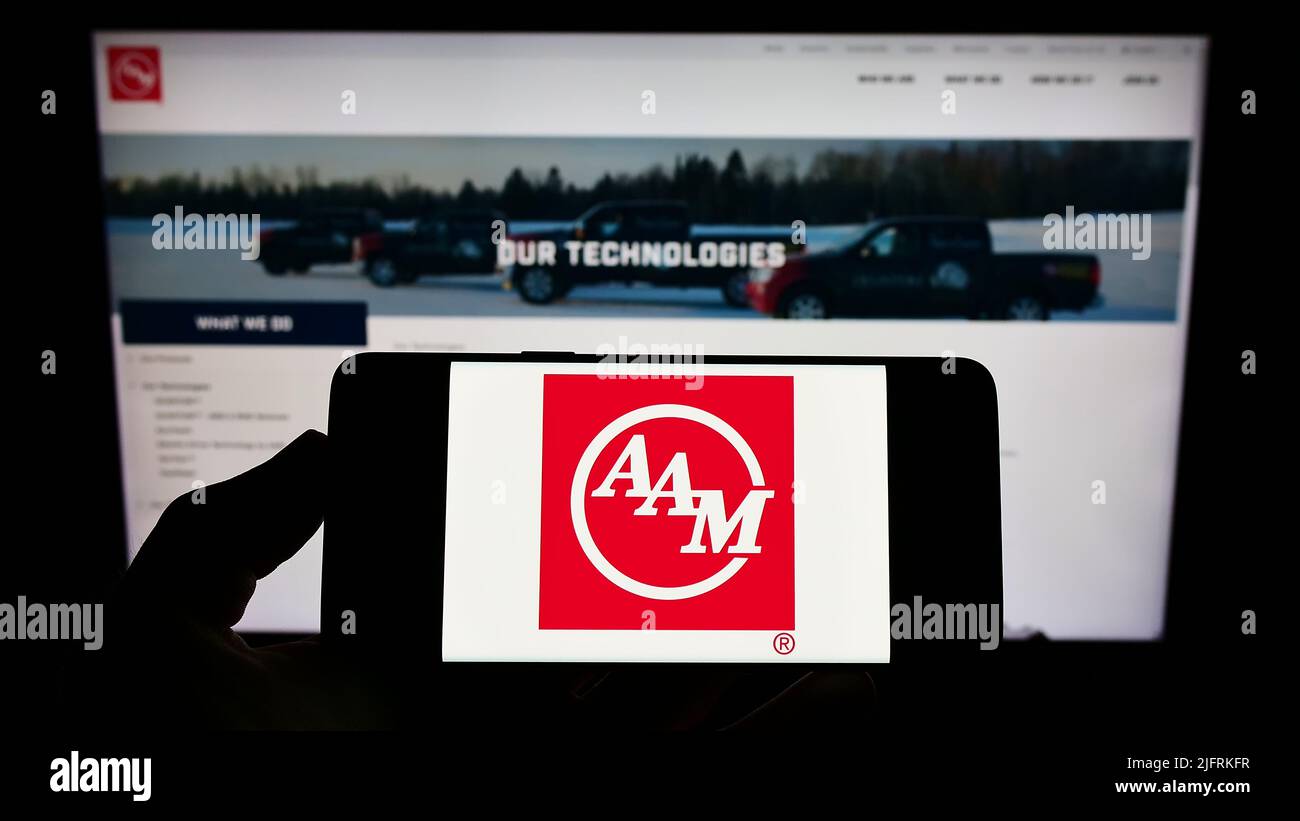 Person holding smartphone with logo of US company American Axle
