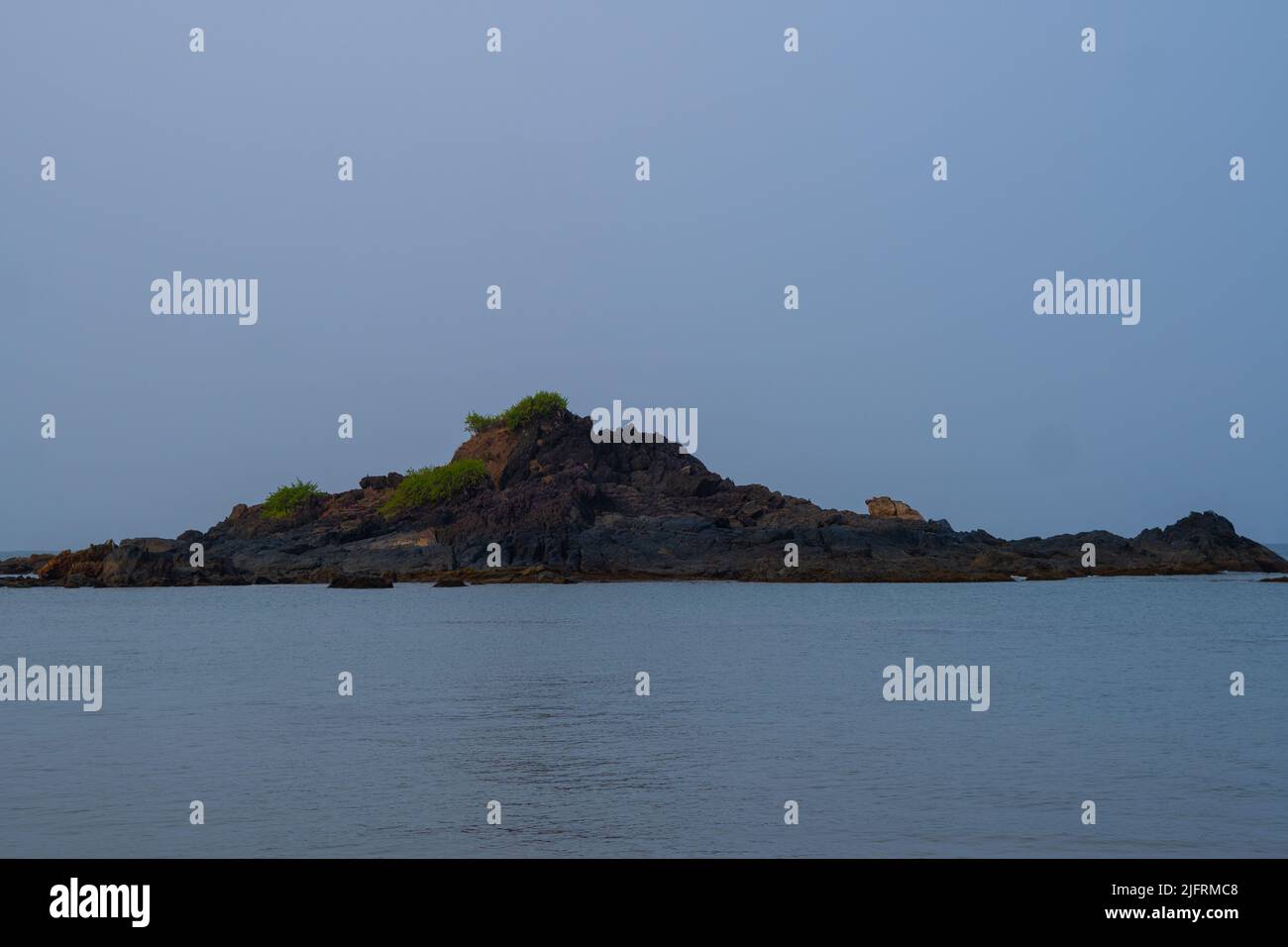 Grass on the rocks . rocks in the middle of a ocean.Clear sky with blue ...
