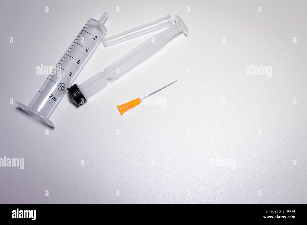 Parts of a medical syringe with a bright orange needle. Space for text. Pharmaceutical images with copy space. Stock Photo