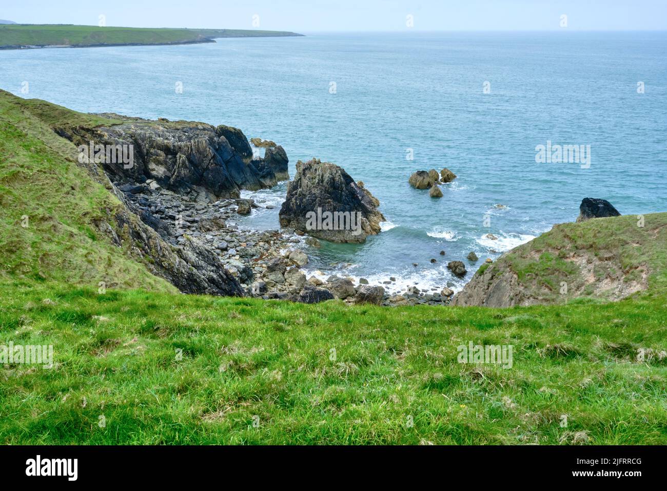 A small cove with central rock on the Wales Coast Path near Porth Colmon on the Llyn Peninsula Stock Photo