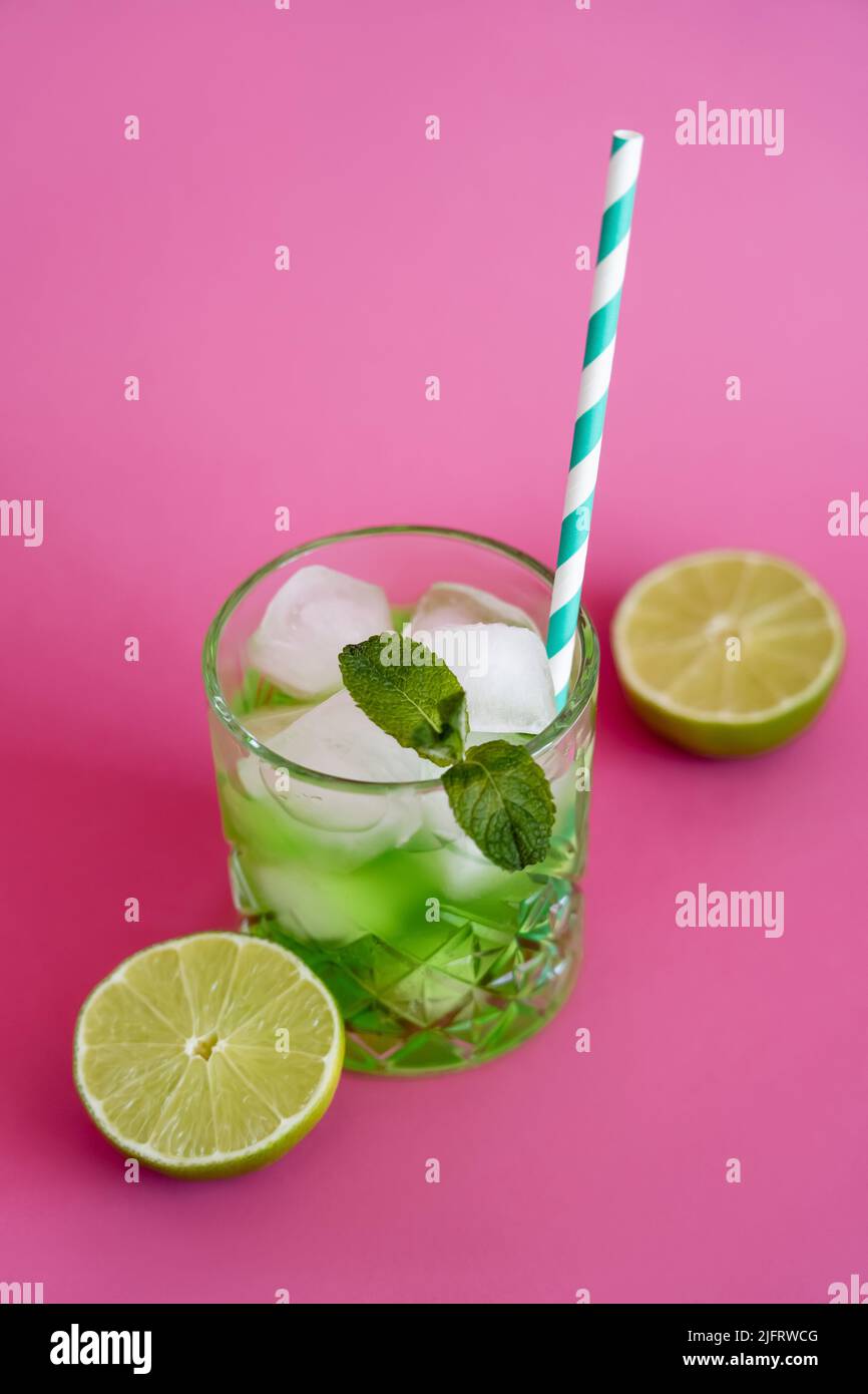 high angle view of frozen ice cubes in glass with mint and green mojito drink on pink Stock Photo