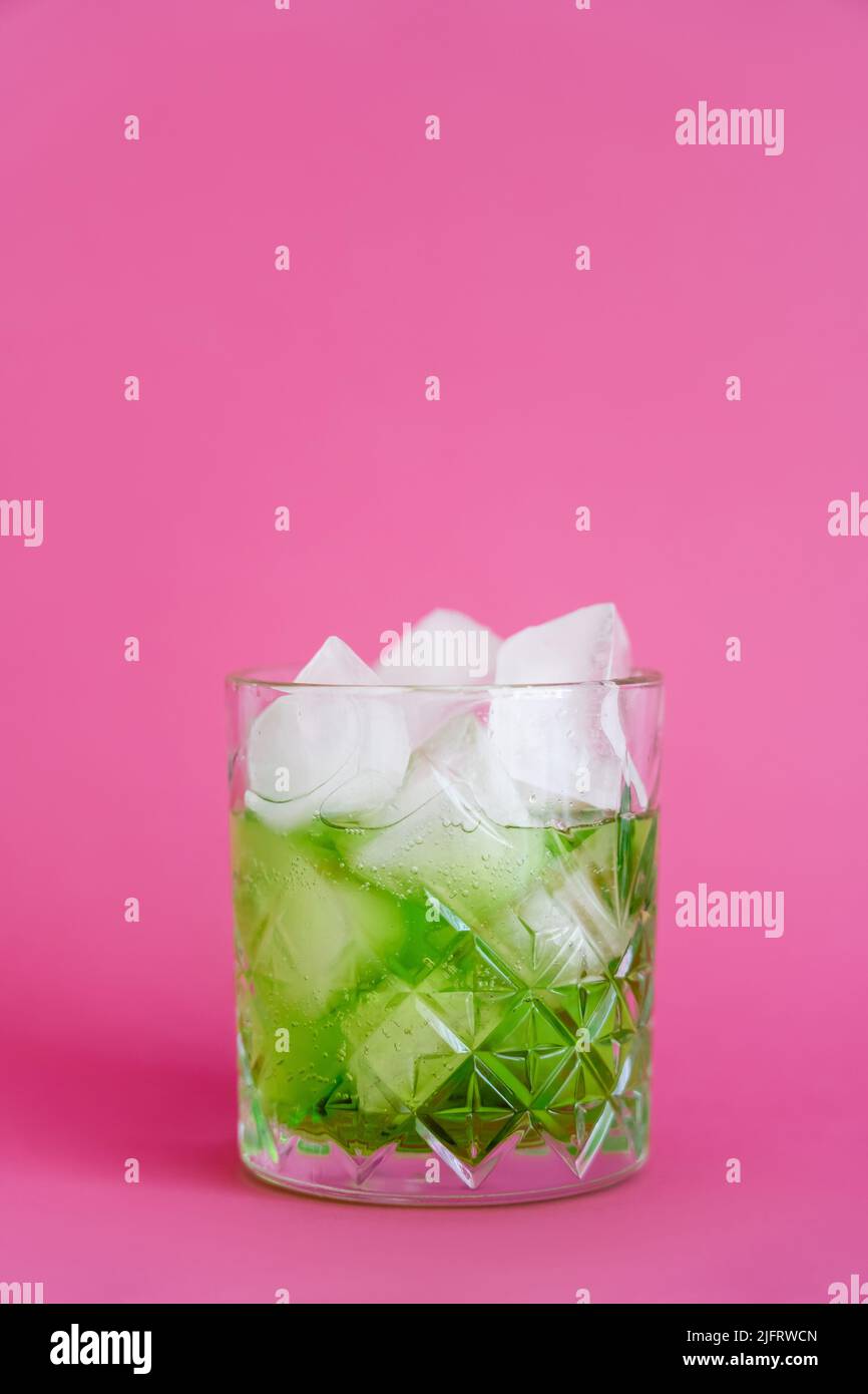 frozen ice cubes in glass with green mojito drink on pink Stock Photo
